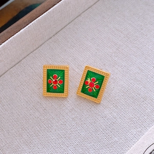 Detail of vintage gold-plated rectangular earrings with green enamel and red rhinestones