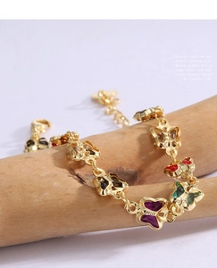 Macro shot of colorful acrylic butterflies on a gold-plated brass chain over wooden prop