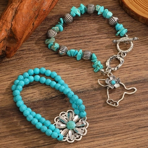 Detail of vintage turquoise bead bracelets with silver cow skull pendant on wood