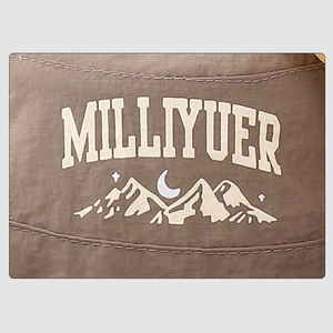 Macro detail of brown quick-dry fabric showing MILLIYUER mountain logo and double stitching