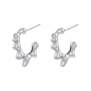 Macro detail of geometric teardrop silver earrings with polished metallic texture