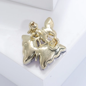 Macro detail of the golden butterfly brooch showing the sturdy back pin fastener