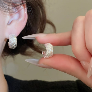 Detail view of silver C-shaped hoop earrings with intricate woven metal texture for women