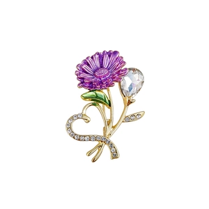 Macro detail of purple daisy brooch with heart-shaped golden stem and crystals