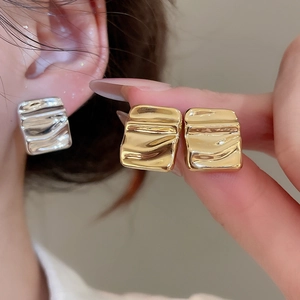 Detailed view of silver and gold textured square earrings with a unique wrinkled metal finish