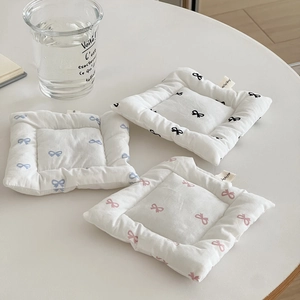 Detailed macro view of quilted bow-pattern fabric coasters in blue, black and pink colors