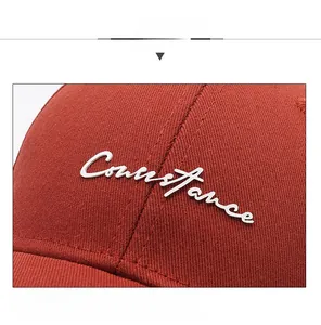 Close-up of white Constance embroidery on a reddish-brown cotton baseball cap detail