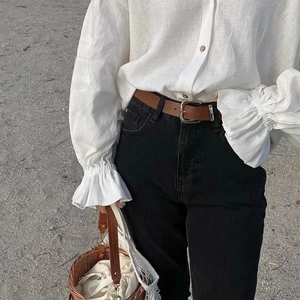 Detail of white long sleeve linen shirt paired with black jeans and brown leather belt