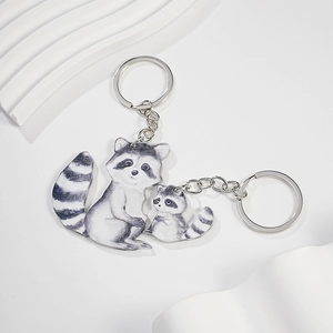 Detail of two raccoon acrylic keychains with silver metal rings on white textured background