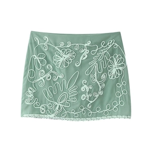 Vue détaillée d'une mini-jupe vert clair avec broderie florale blanche et bordure en dentelle