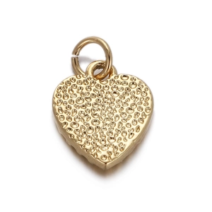 Macro shot of gold heart-shaped metal pendant with unique hammered texture and jump ring