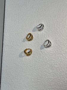 Close-up of gold and silver double-hoop geometric earrings on textured background