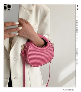 Detail of pink crescent bag showing vertical textured design and gold metal buckles