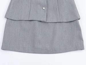 Detail view of the layered hem and silver button on grey crepe dress set fabric