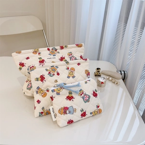 Close-up of three quilted cotton pouches with vintage floral prints and zip closure
