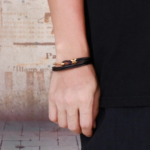 Close-up of men's double-wrap black leather bracelet with a gold stainless steel clasp