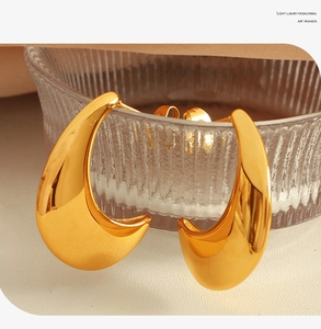 Macro detail of golden water drop earrings on textured glass with elegant mirror finish
