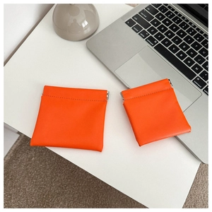 Detail of bright orange leather mini coin purse with metal spring clip closure mechanism