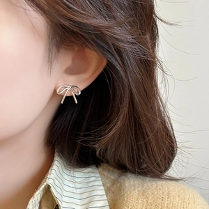 Elegant silver bow stud earrings for women featuring a minimalist ribbon design on ear
