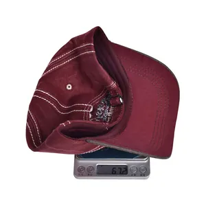 Detail view of burgundy baseball cap on digital scale showing weight of 67.2 grams