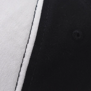 Detailed macro view of black and white cotton baseball cap panels with reinforced stitching