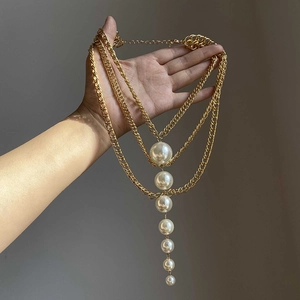 Close-up of multi-layer gold chain necklace with vertically aligned white pearls