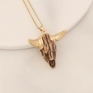 Close-up of bohemian bull skull pendant with brown texture and gold-plated horns