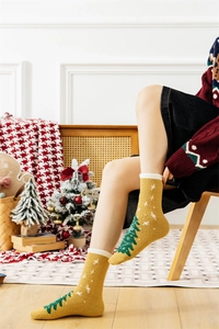 Close-up of ginger yellow plush Christmas socks with a green tree pattern and cozy knit