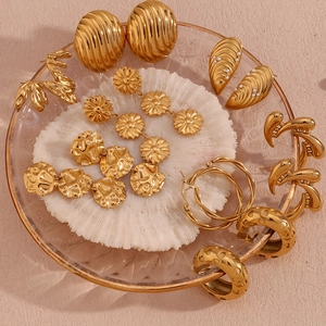 Detail view of 18K gold-plated geometric hollow earrings in a glass jewelry dish