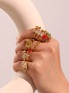 Macro detail of stacked 18k gold plated insect and strawberry rings with zircon