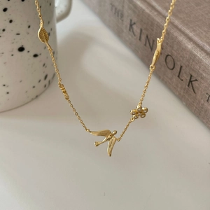 925 silver gold necklace featuring bird flower and leaf pendants hanging on a white mug