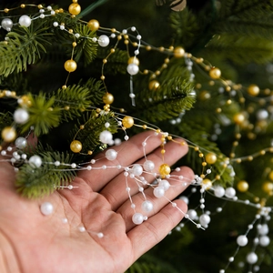 White and gold pearl bead garland chain hanging on Christmas tree branches