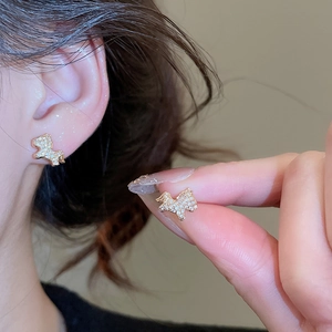 Close-up of gold-plated bow earrings with sparkling zircon crystals on model ear