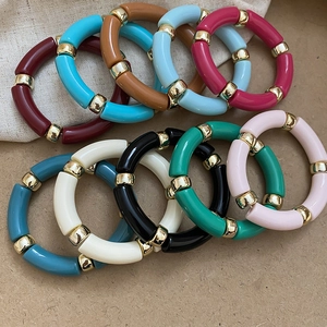 Detailed macro view of colorful acrylic tube bead bracelets with golden metal spacers