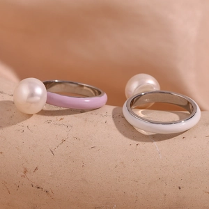 Detail of stainless steel rings with purple and white enamel and large pearl accents