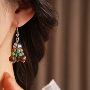 Macro view of Bohemian earrings with dark wood and turquoise beads on a model