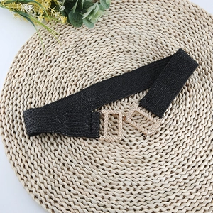 Elastic woven belt in black with gold textured metal buckle on a minimalist background