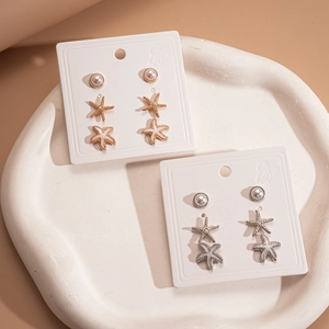 6-pair set of gold and silver starfish and pearl stud earrings on a display tray