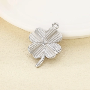 Detailed view of silver clover pendant with textured surface on a neutral background
