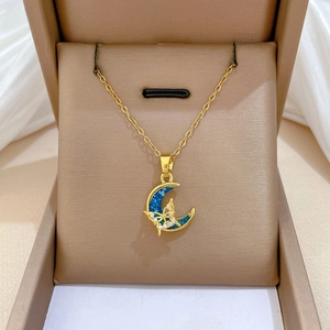 Macro shot of gold-plated moon and butterfly pendant with crystal pavé and blue shell inlay
