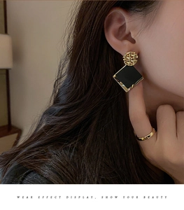 Close-up of elegant black square earrings with gold woven texture on model