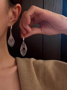 Close-up of elegant silver layered hollow rhombus earrings with zircon on a model