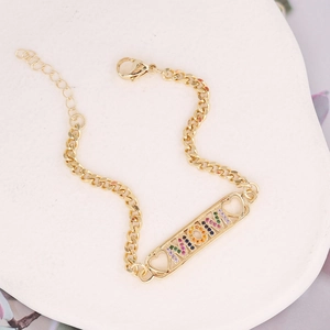 Macro shot of gold MOM plate with rainbow cubic zirconia on a Cuban link bracelet