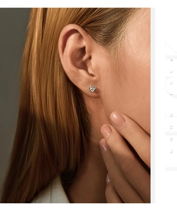 Close-up of heart-shaped moissanite silver earring worn on model ear for detail