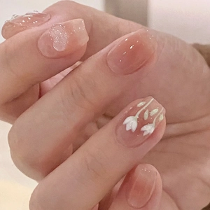 Macro detail of jelly pink press-on nails with white camellia flowers and sparkling heart sequins