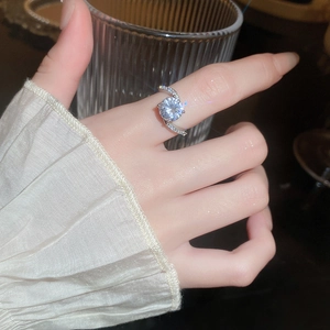 Close-up of a silver geometric ring with large zircon and twisted band on a finger