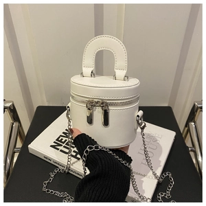 Gros plan d'un sac seau cylindrique blanc avec bandoulière en chaîne argentée et zip