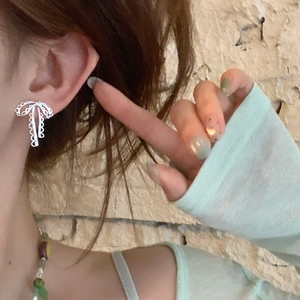 Gros plan d'un modèle portant des boucles d'oreilles nœud argenté ajouré chic