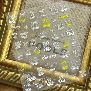 Detail of 3D nail art stickers with silver bow and cherry designs on vintage frame