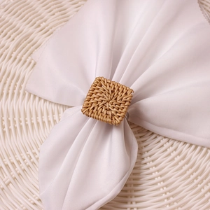 Macro shot of a square woven rattan napkin ring on a white cloth with a natural texture